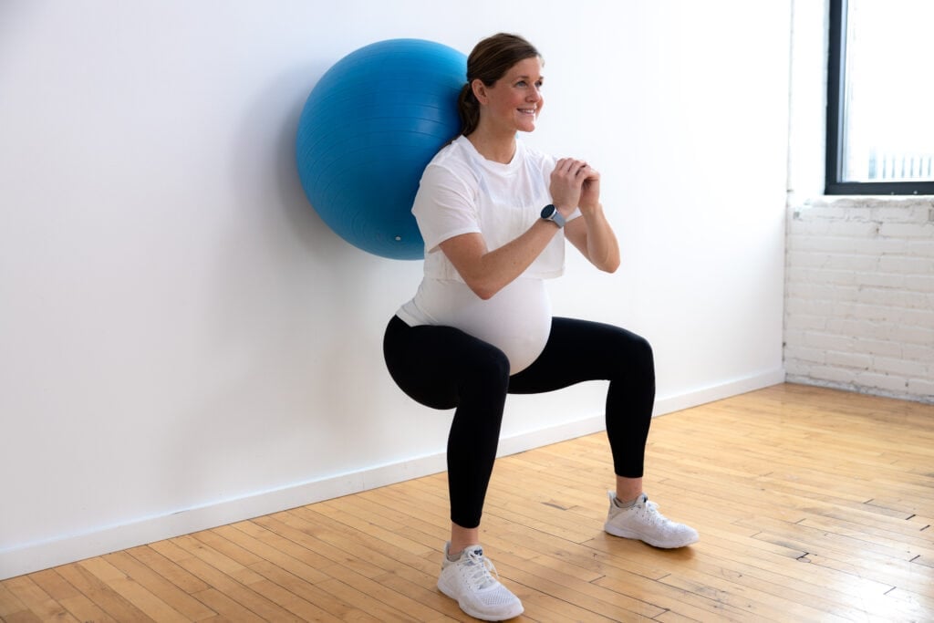 woman performing wall squat with pregnancy exercise ball