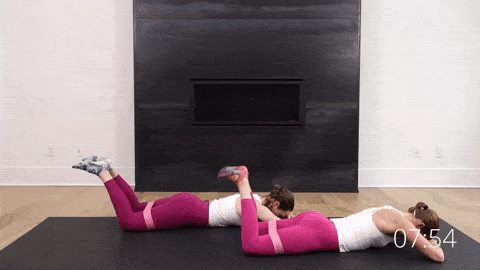 two women lying on their stomach performing prone froggy leg lifts to target the glutes