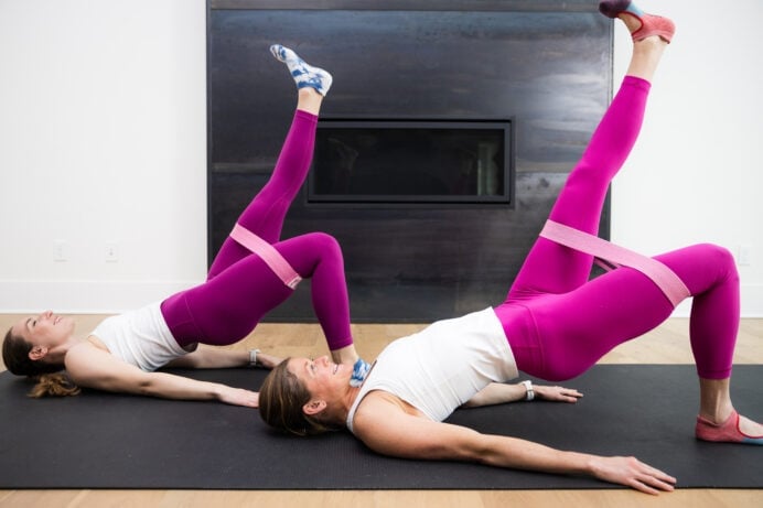 two women performing a single leg glute bridge with a mini loop resistance band