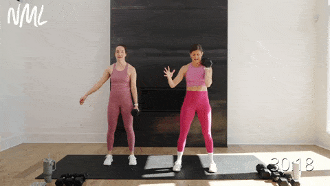 two women performing an uneven dumbbell squat, one with a dumbbell front racked and one woman with the dumbbell by her side in an emom workout