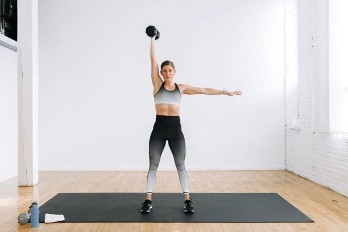 Woman performing an uneven dumbbell press as part of one dumbbell workout