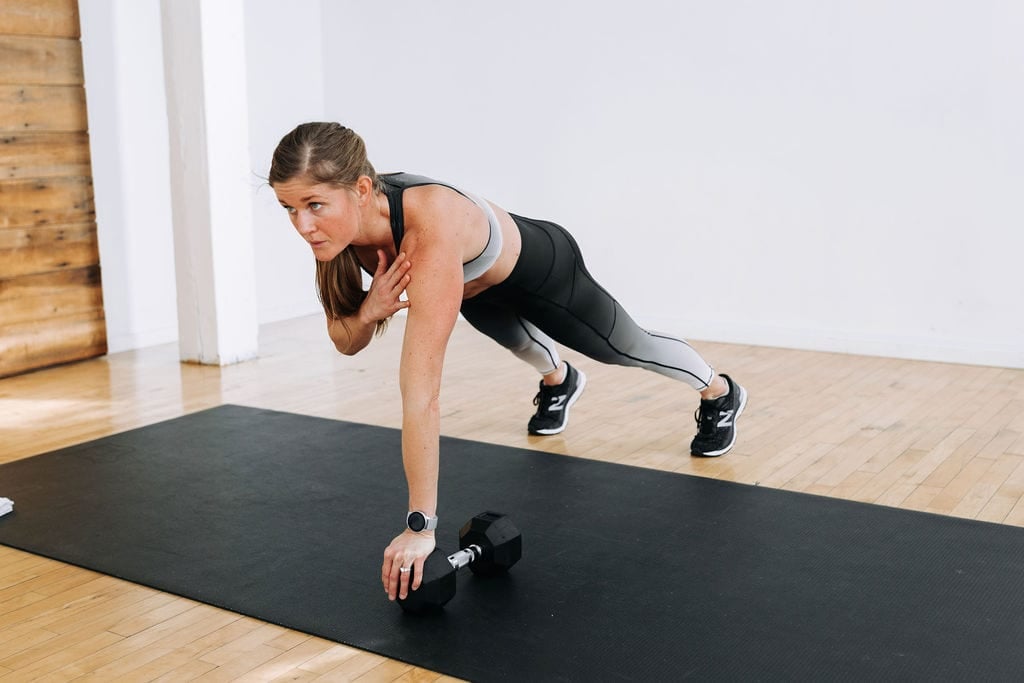 Woman performing a push up and shoulder tap as example of single dumbbell workout
