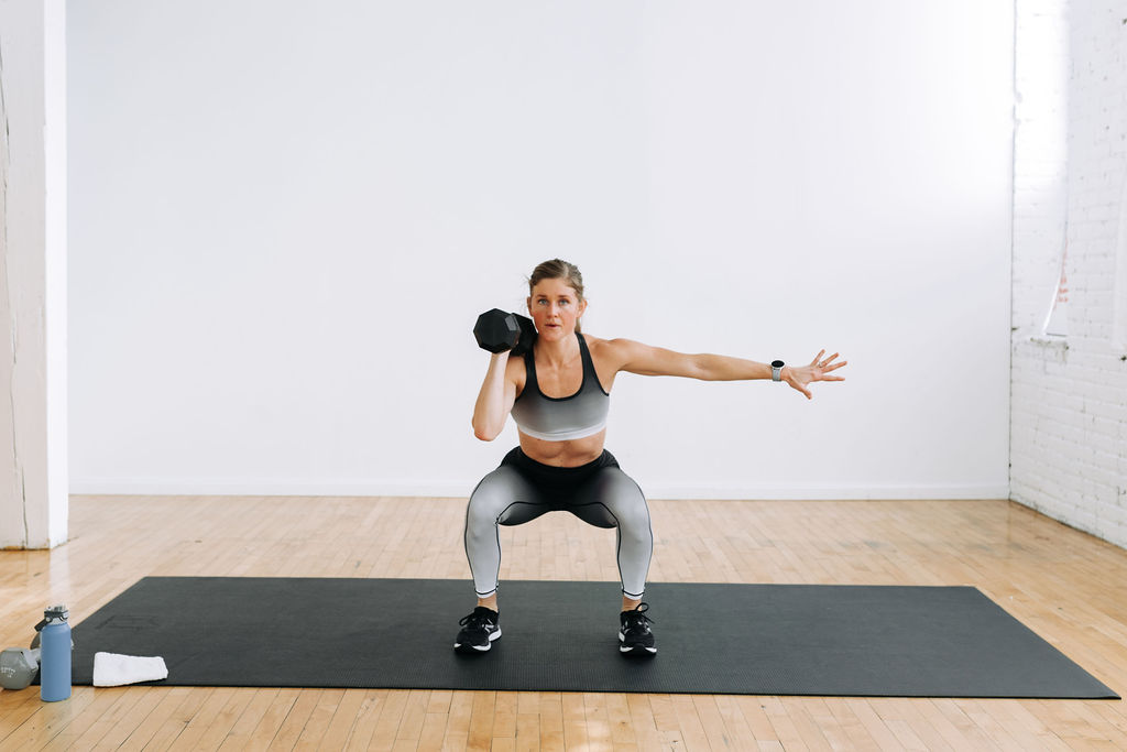Woman performing a single uneven squat with one dumbbell as part of one dumbbell workout