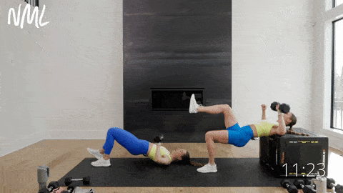 one woman performing a single leg glute bridge and single arm chest press while supported on a box, another woman performing a single leg glute bridge and chest press from the ground