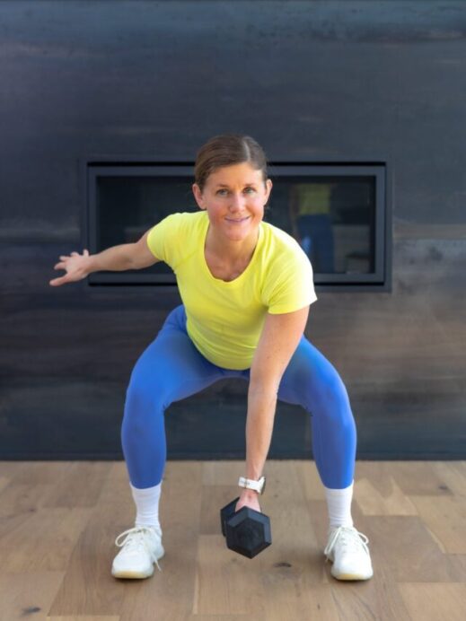 Woman performing a low squat with a dumbbell as part of lower body workout with dumbbells