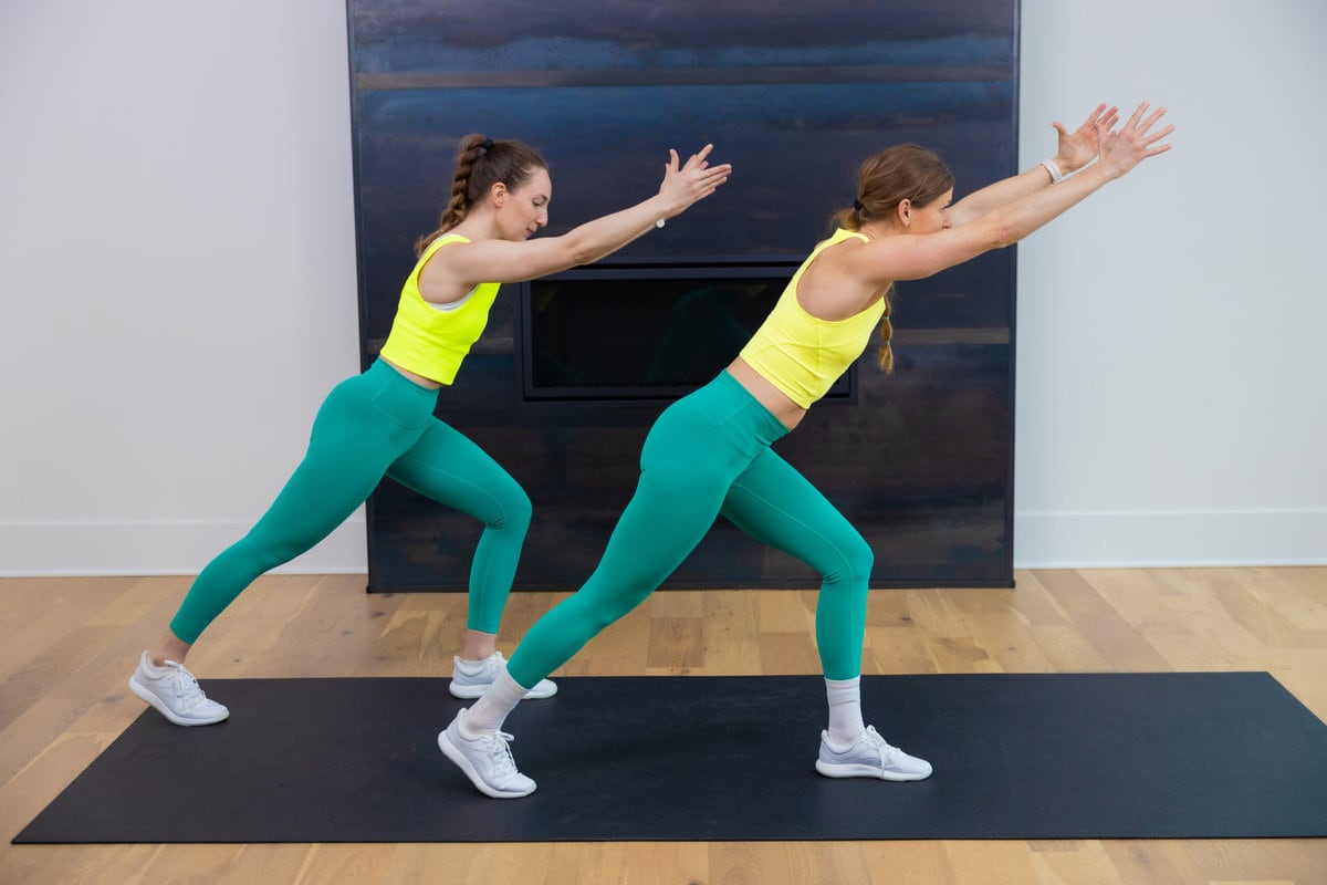 two women performing a knee slam in a standing cardio workout at home