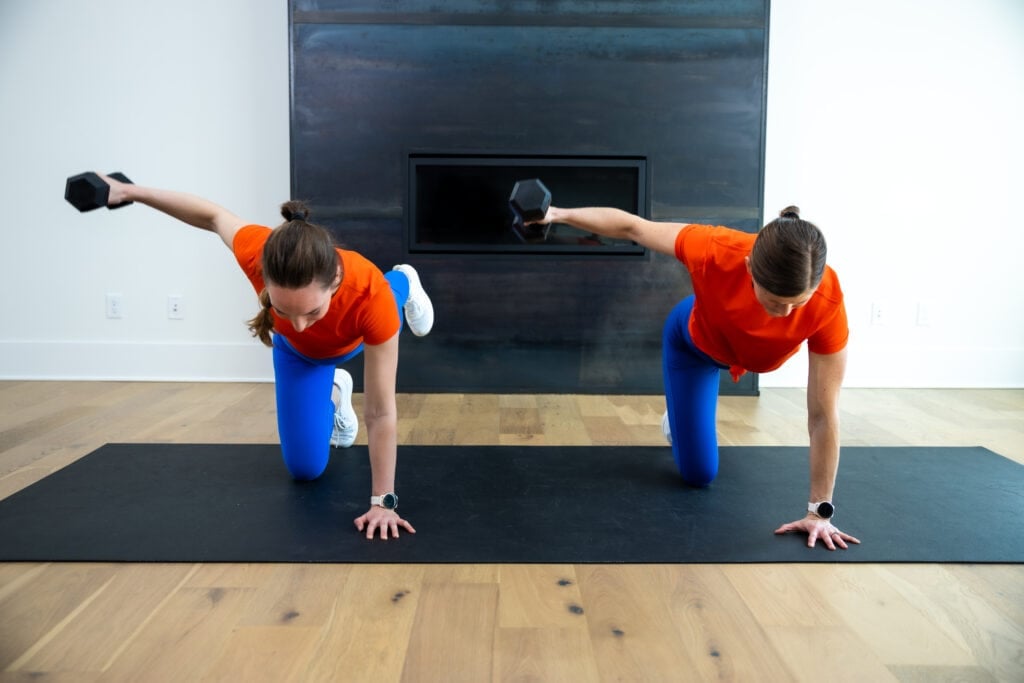 two women performing a single arm back fly from a bird dog position in a back and bicep workout at home