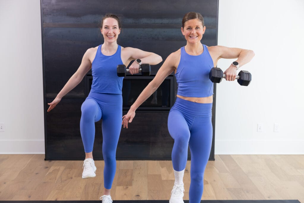 two women performing a dumbbell high pull in a full body strength workout