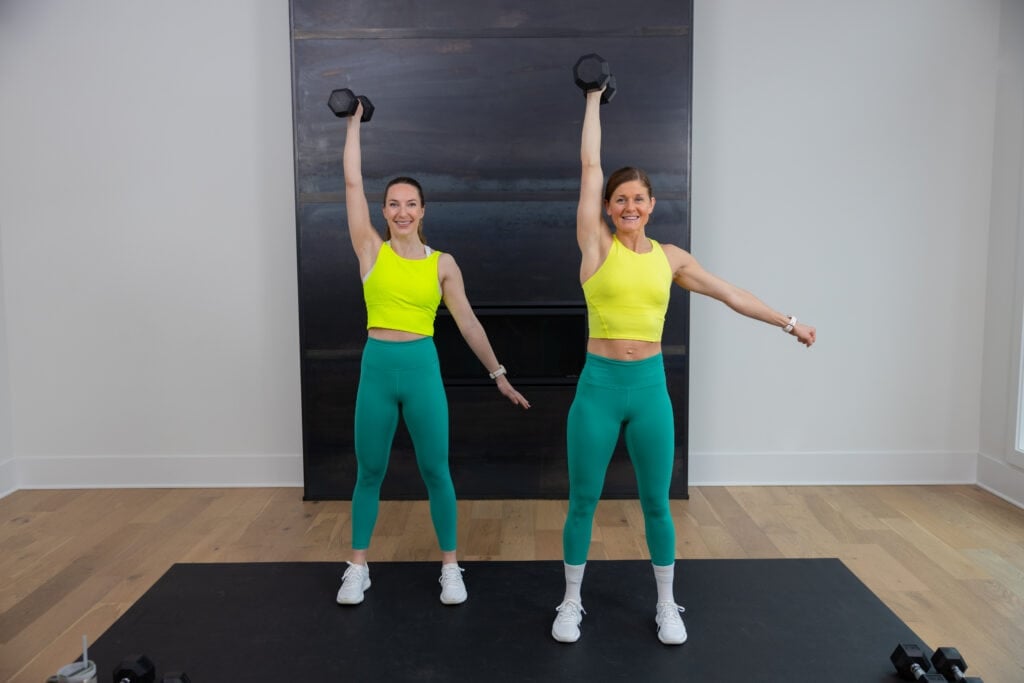 two women holding a dumbbell overhead as part of a single arm dumbbell snatch in a total body workout