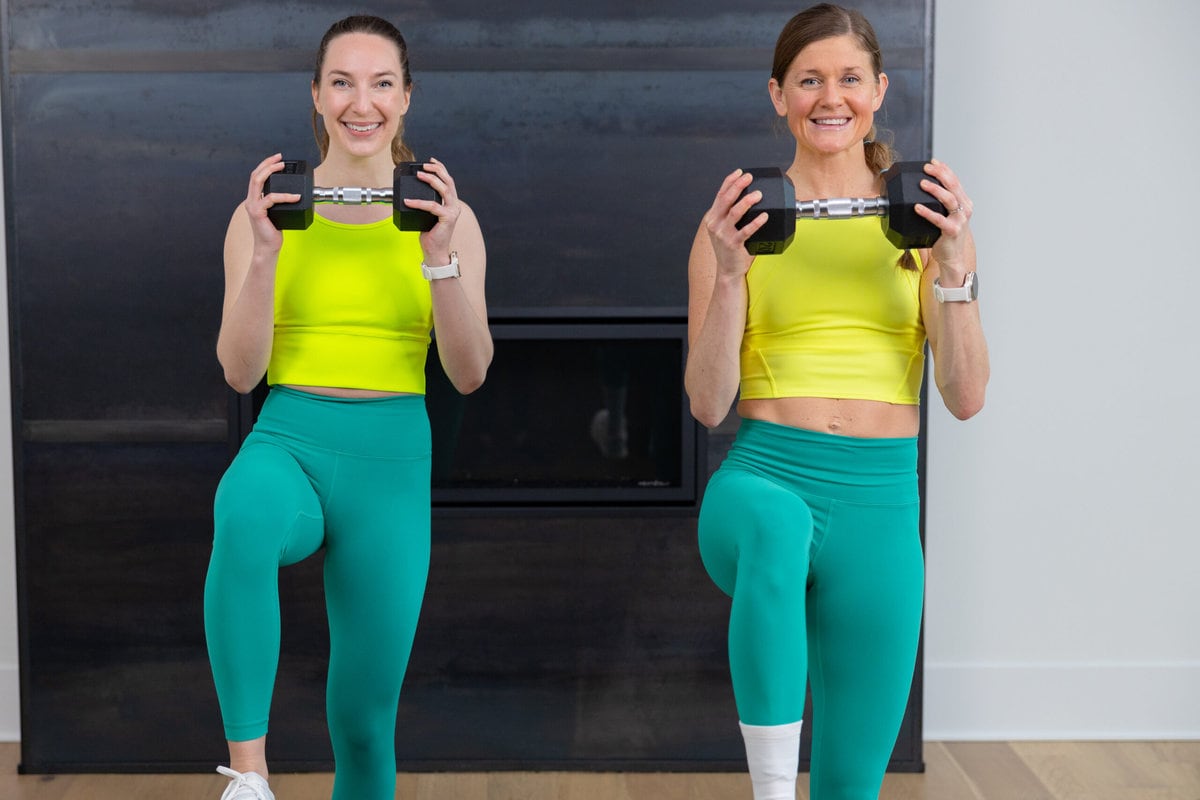 two women holding a dumbbell at chest level with a high knee hold in a full body workout
