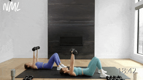 two women performing a dumbbell chest press in a chest workout for women