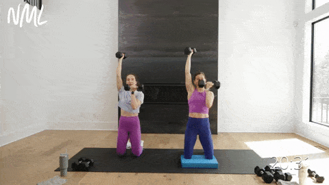 two women performing a kneeling single arm shoulder press in an upper body workout