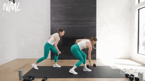 Two women performing a landmind row and press as part of standing sweaty ab workout