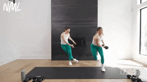 two women performing skaters with dumbbells as part of standing workout to target the abs