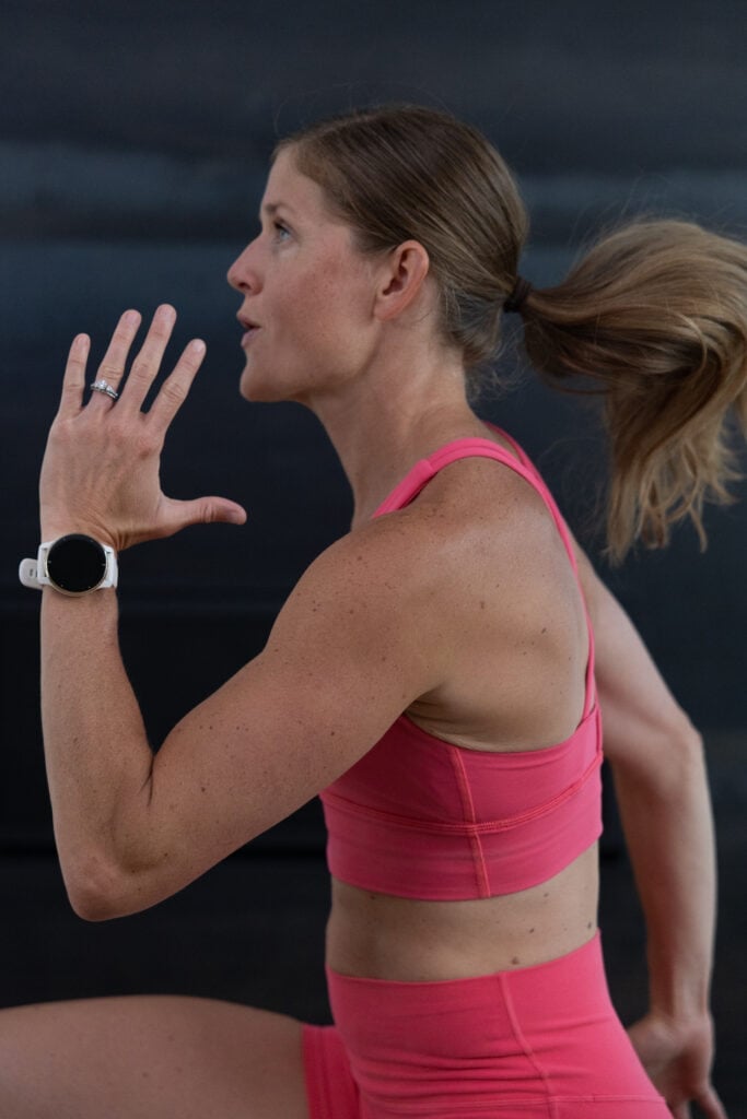 woman performing high knees while wearing a Garmin smart watch