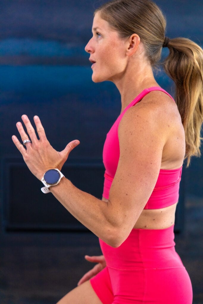 woman performing high knees while wearing a Garmin smart watch