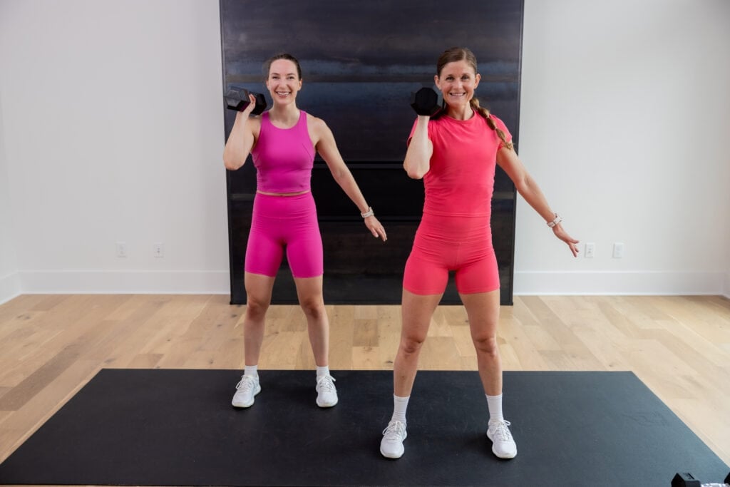 two women performing a dumbbell hold at shoulder height in a total body strength and hiit workout