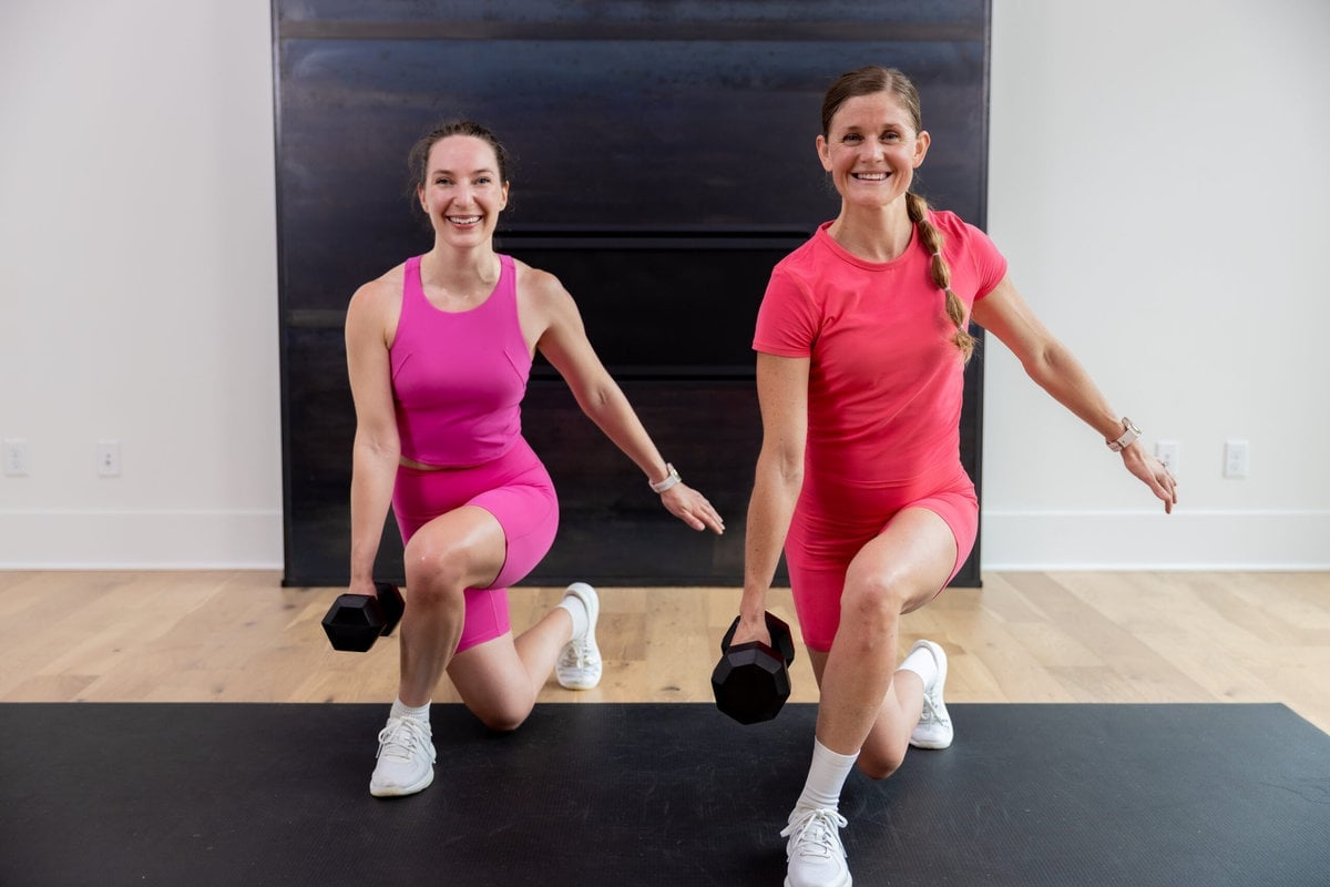 two women performing a curtsy lunge in a hiit workout with weights