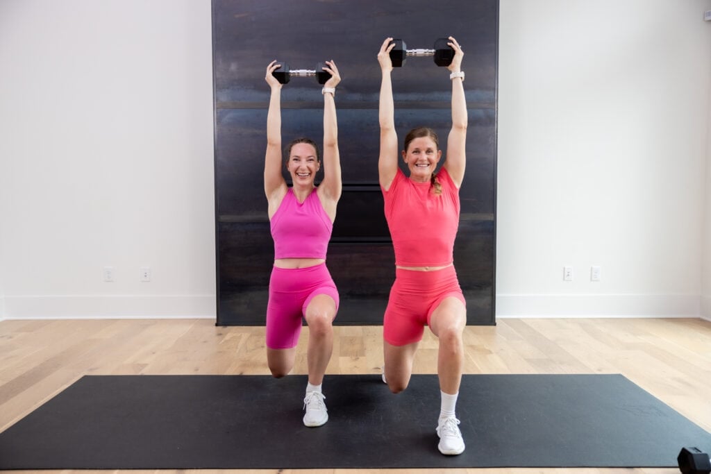 two women performing a reverse lunge and overhead dumbbell press in a 30-minute HIIT workout