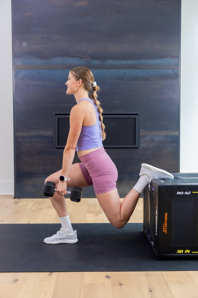 Woman performing a rear foot elevated split squat (bulgarian split squat) as part of quad workout