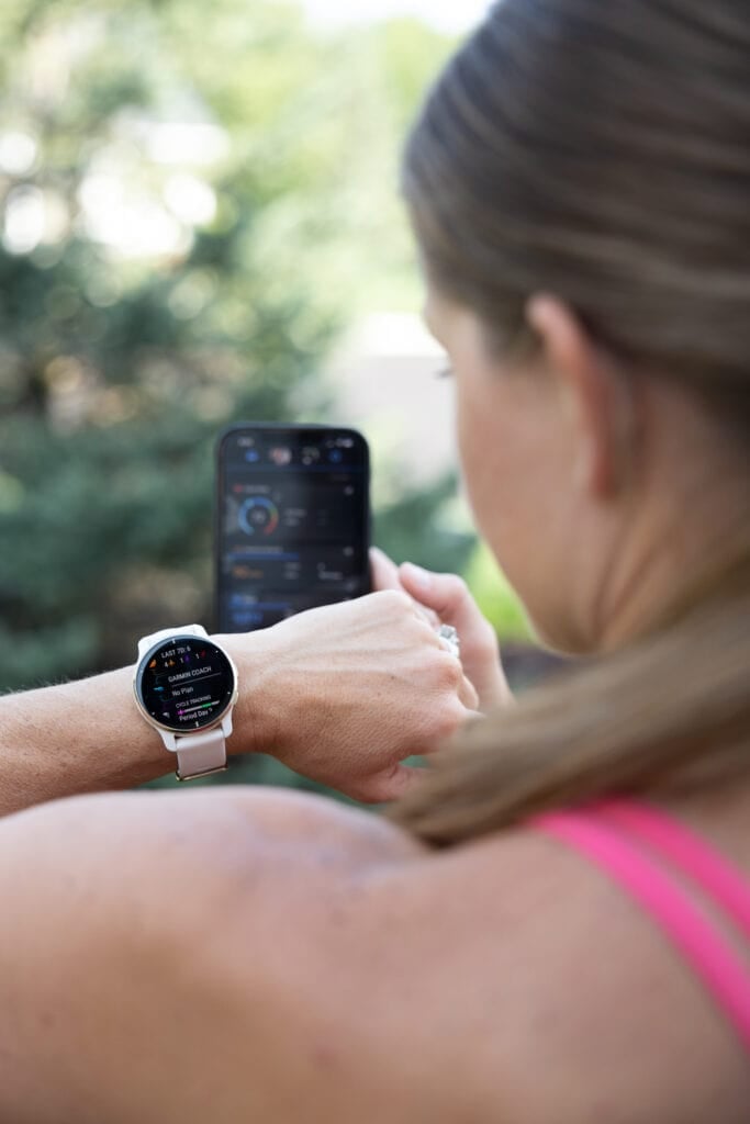 Woman wearing a Garmin Venu 2 Plus showing the Garmin coach along side the Garmin Connect app on phone | discount codes