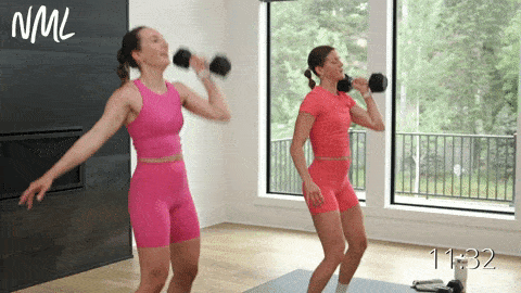 two women performing a single arm push press in a total body HIIT workout