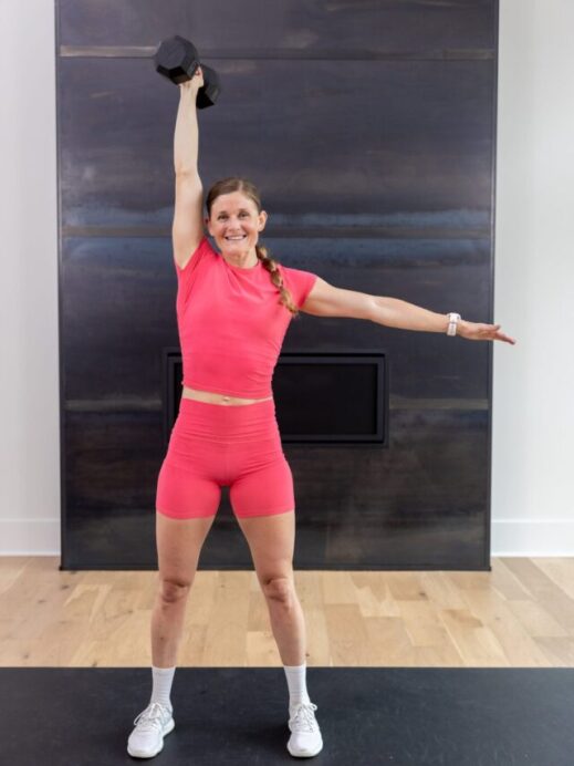 woman performing a single arm press in a total body strength and hiit workout
