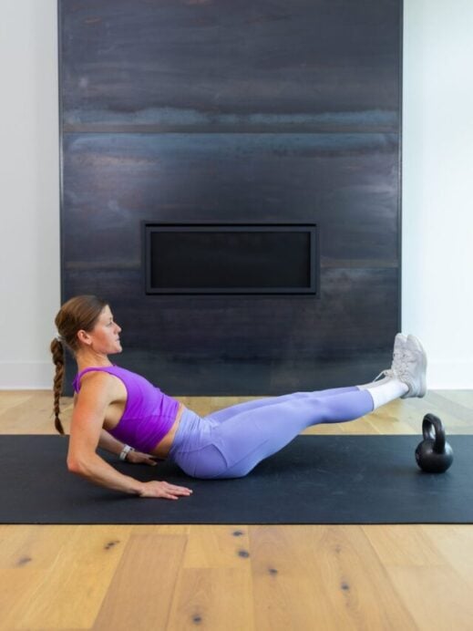 woman performing a leg lift and crunch with a kettlebell