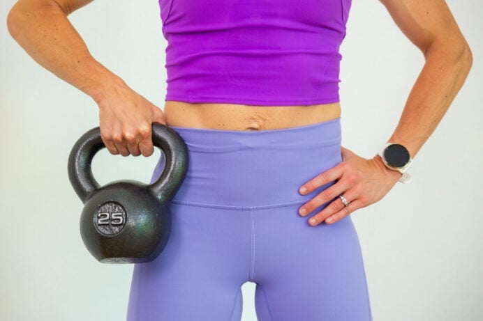 Kettlebell ab workout - close up shot of woman holding kettlebell by her hip while flexing abs