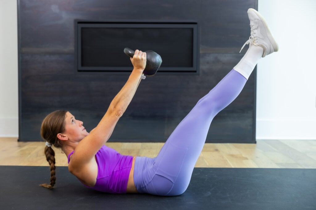 woman performing a kettlebell chest press as part of kettlebell abs routine