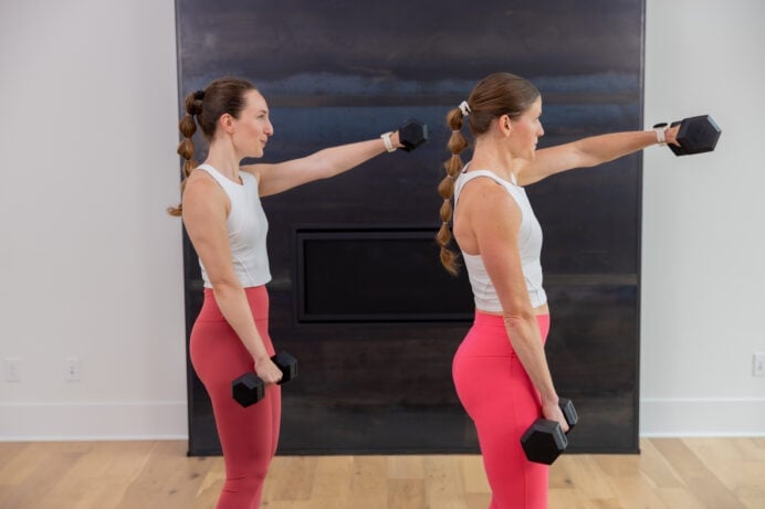 two women performing a single arm front raise in an arm workout with dumbbells