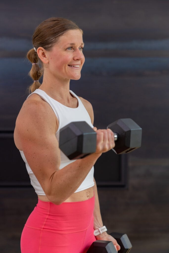 woman performing a single arm bicep curl in an arm workout with dumbbells