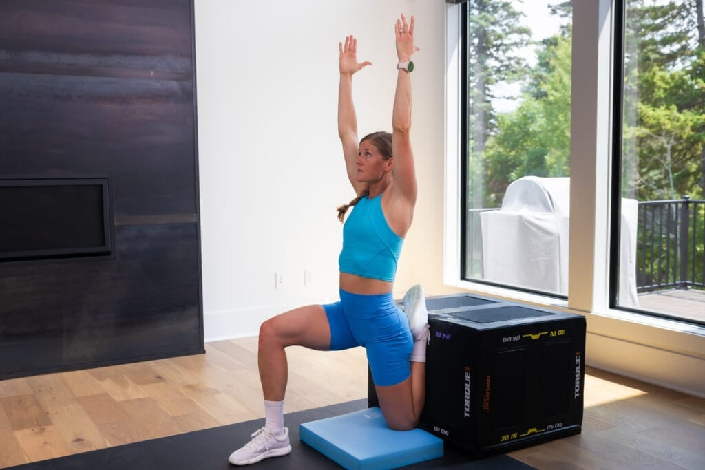 Woman performing a couch stretch to increase range of motion and hip mobility in her left leg. Arm straight overhead, shoulder blades squeezed together, and her right knee directly over her ankle | mobility training | mobility exercises 