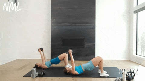 two women performing a glute bridge and tricep skull crushers in a full body kettlebell workout