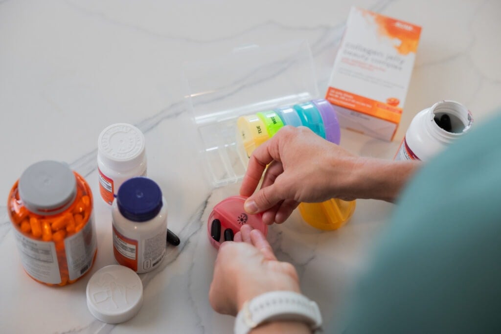 woman filling pill organizer with best supplements for women
