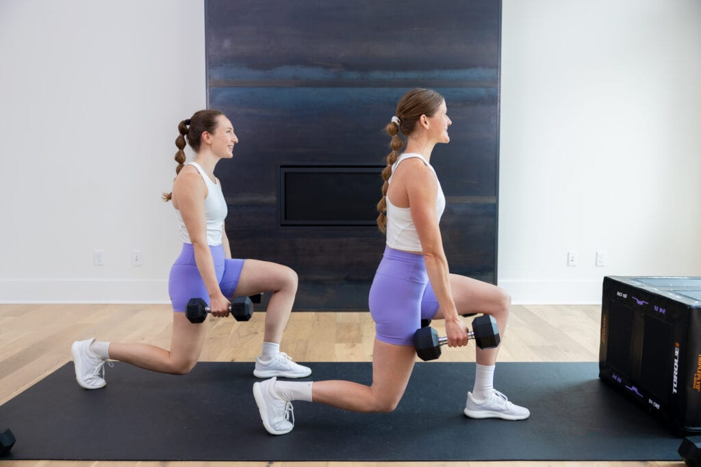 two women performing reverse lunges as example of dumbbell leg exercises