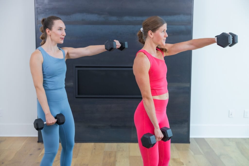 two women performing a single arm raise as example of dumbbell shoulder exercises