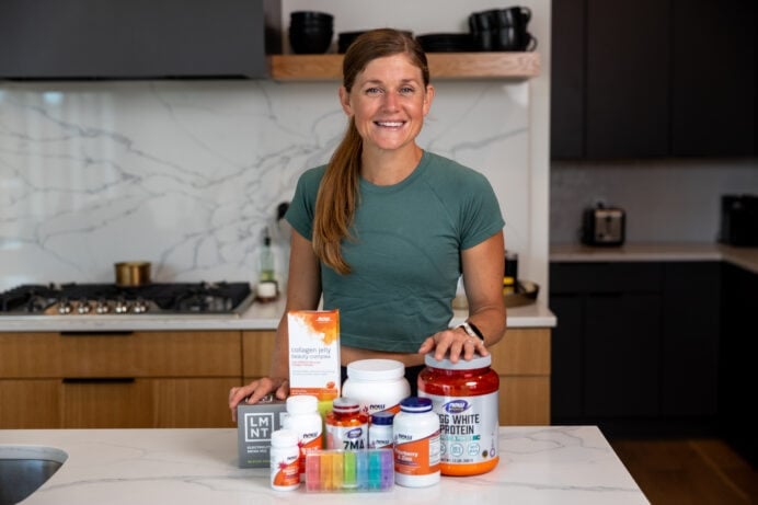 Woman posing in kitchen with supplements lined up showing best supplements for women