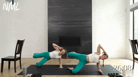 two women performing a modified side plank and leg lift with a heel stamp in a barre sculpt workout at home