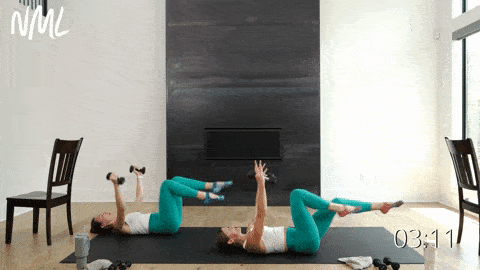 two women performing bicycle crunches and chest flys with light weights in a barre workout