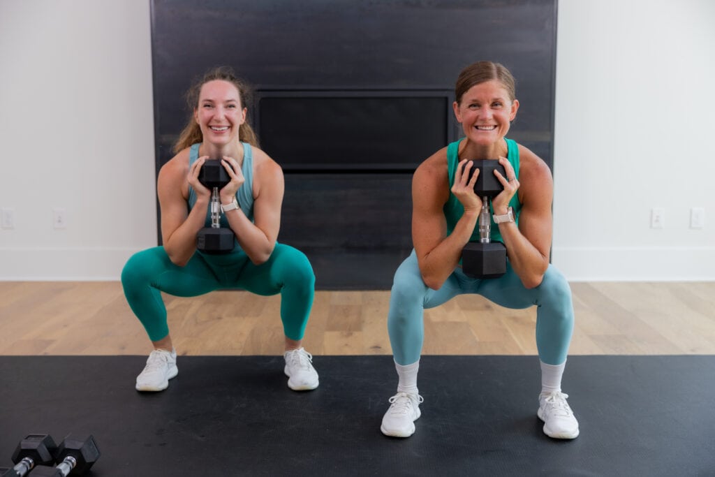 two women performing a goblet squat in an AMRAP workout