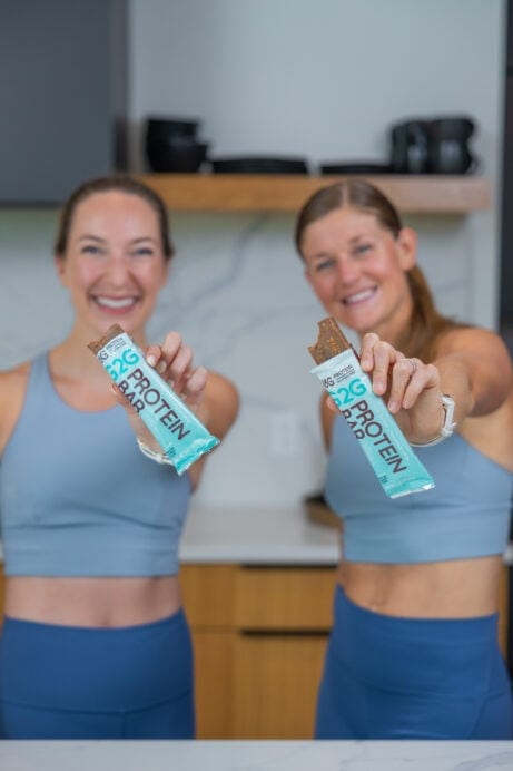 two women eating protein bars as part of the best high protein snacks