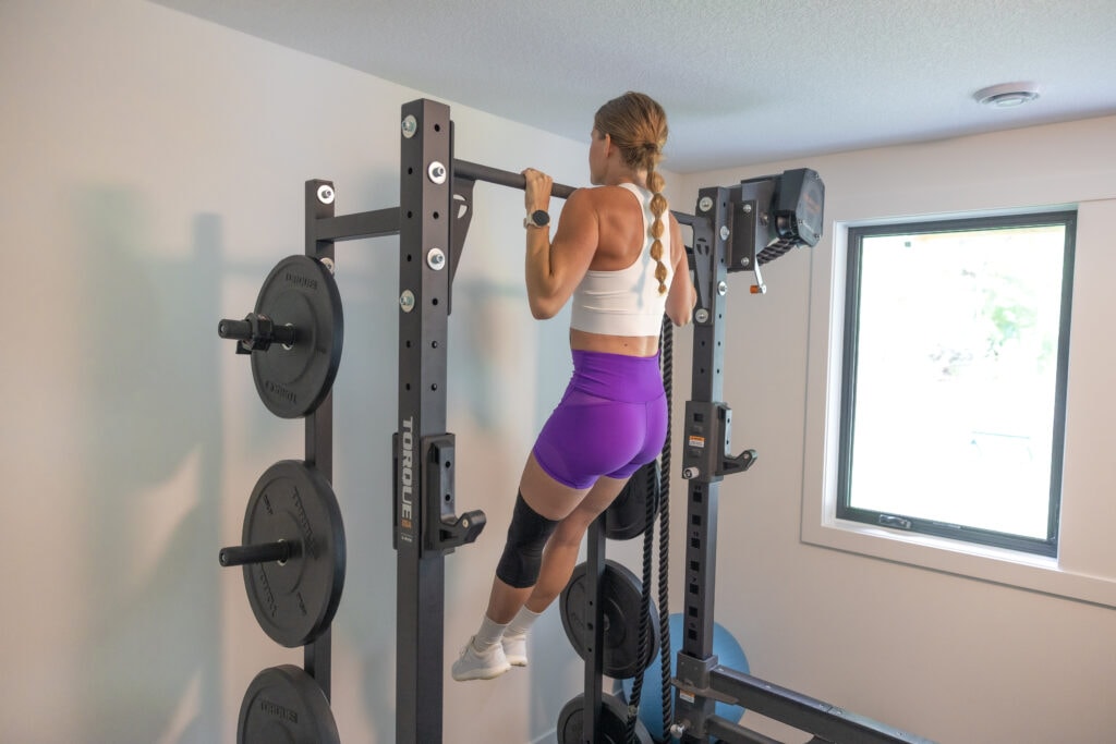 Women doing negative pull ups at home with her shoulder blades activated. Step-by-step guide of how to do a pull up to start doing pull ups weekly.