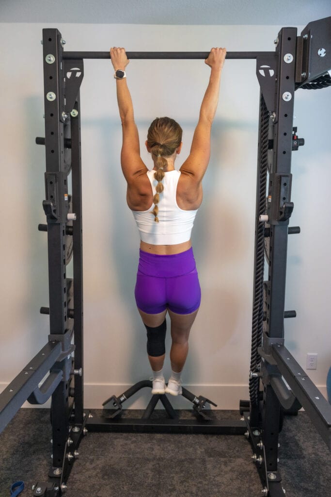 Woman hanging on the bar in preparation for showing how to do a proper pull up.  