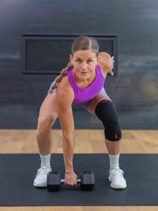 woman performing a dumbbell snatch as example of compound exercises