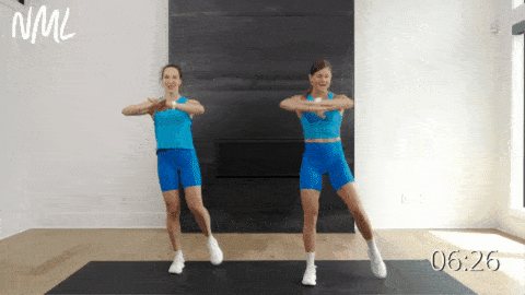 two women performing a standing crunch with an oblique rotation as part of ab circuit workout