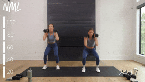 two women performing dumbbell squat thrusters as part of a dumbbell thrusters workout
