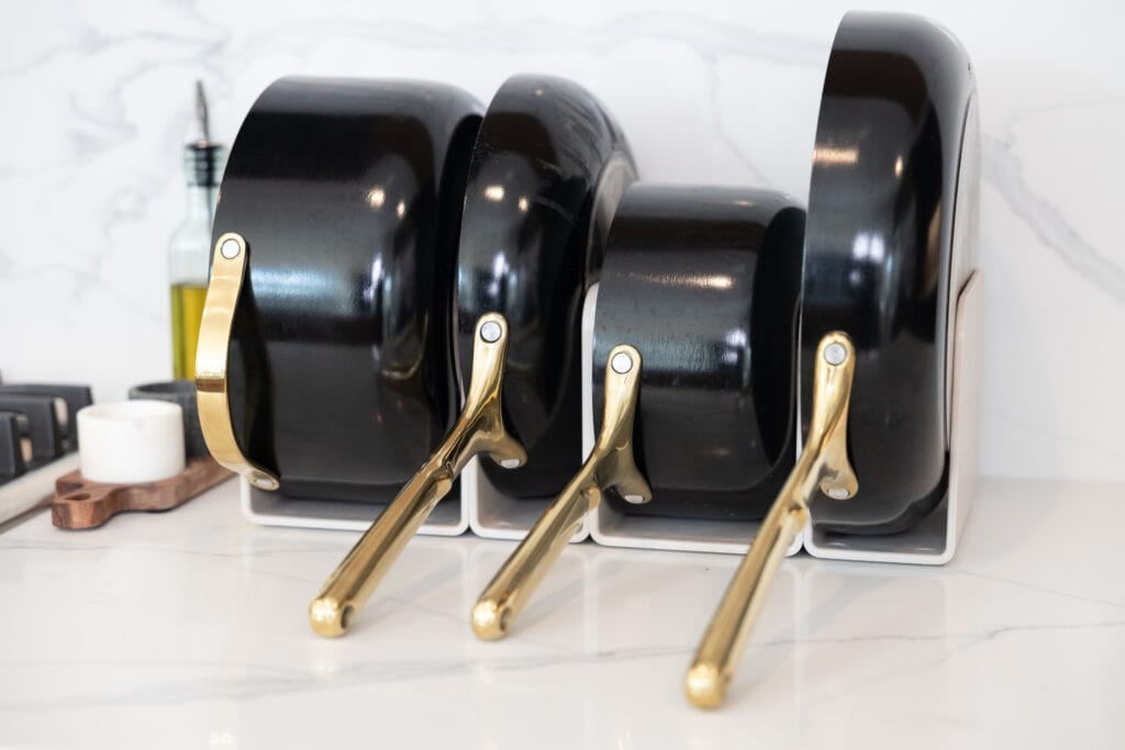 Kitchen Essentials. Caraway cookware set all set up in a white kitchen next to stove.