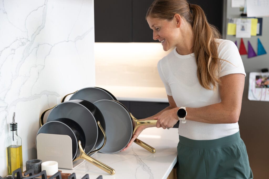 Women in her kitchen using her stainless steel caraway cookware set to meal prep for the week. Kitchen essentials. 