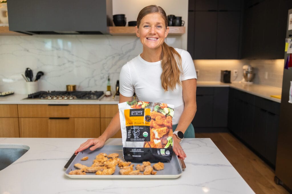 Women in her kitchen meal prepping a sheet pan dinner, using her caraway large sheet pan. Kitchen Essentials.